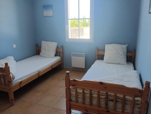 Cette chambre comprend 2 lits dans une chambre dotée de murs bleus et d'une fenêtre. dans l'établissement Maison 3 étoiles près des plages 3 chambres, à Saint-Hilaire-de-Riez