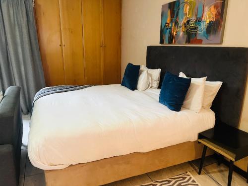 Un dormitorio con una gran cama blanca con almohadas azules. en Mbizo Cozy Retreat- Lofts at Loftus, en Pretoria