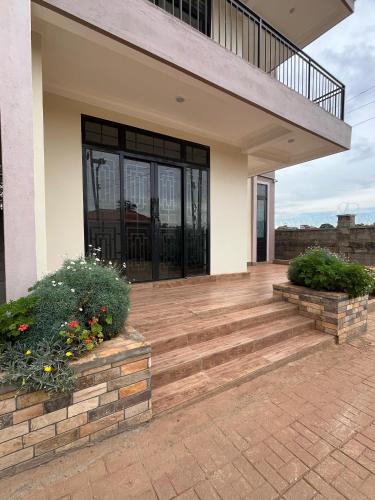 a house with a porch with stairs and flowers at Zaya Residency in Kampala