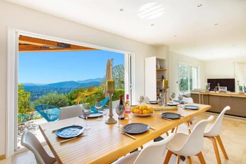 a dining room with a table and chairs and a large window at Villa Bel Horizon by Villa Plus in Cabris