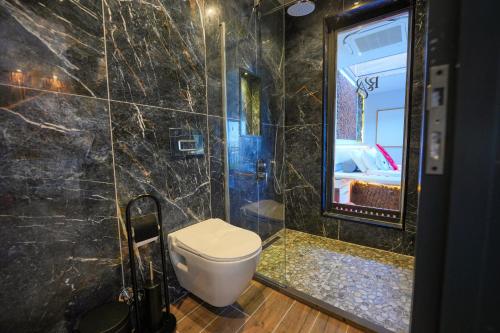 a bathroom with a toilet and a shower with a mirror at Ramitos Hotel in Turunc
