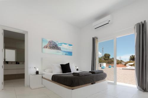a white bedroom with a large bed and a large window at Villa Boutique Can Plana in Sant Jordi