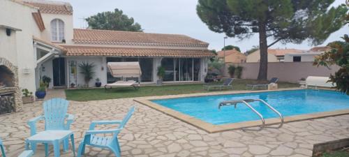 - une piscine avec des chaises bleues et une table dans l'établissement La paillote des Ninous, à Bassan