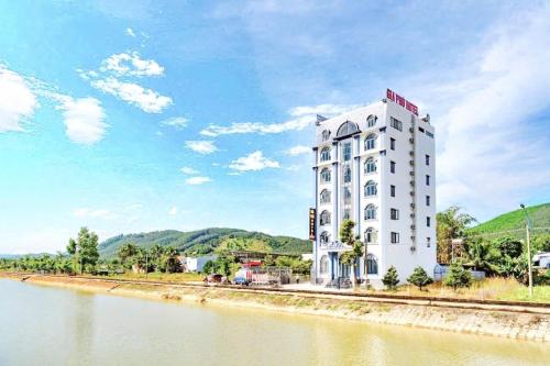 a tall white building next to a river at Gia Phú Hotel Bình Thuận in Tánh Linh