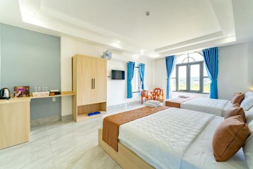 a large bedroom with two beds and a desk at Gia Phú Hotel Bình Thuận in Tánh Linh