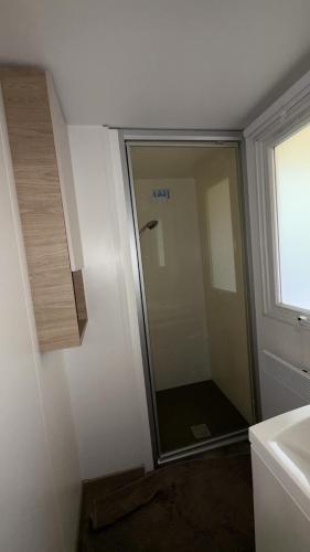 une salle de bain avec une douche en verre avec un lavabo dans l'établissement Mobil home climatisé 8 couchages 3 CHAMBRES 222 SIBLU LES CHARMETTES, aux Mathes