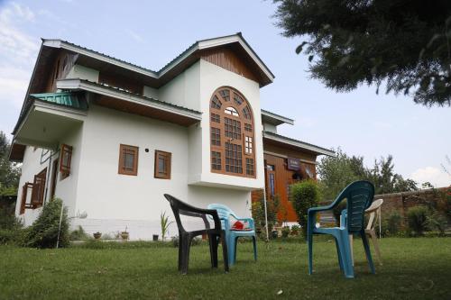three chairs sitting in the grass in front of a house at The Bilt farmhouse in Srinagar