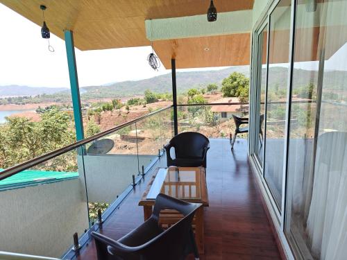 a balcony of a house with a table and chairs at Nisarga Lake Resort Tapola in Satara
