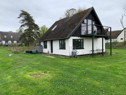 a white house with a black roof and a yard at Hønsehuset in Præstø