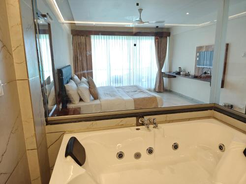 a bathroom with a tub and a bed in a mirror at Nisarga Lake Resort Tapola in Satara
