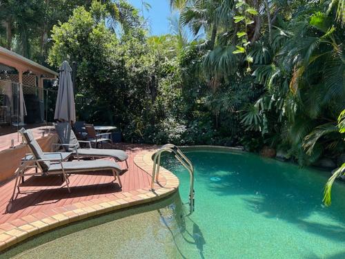 a swimming pool with two lounge chairs and an umbrella at South Pacific Bed & Breakfast in Clifton Beach