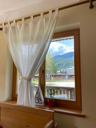 a window with a curtain and a view of a mountain at Apartments Vršič on the ski slope with free parking in Kranjska Gora