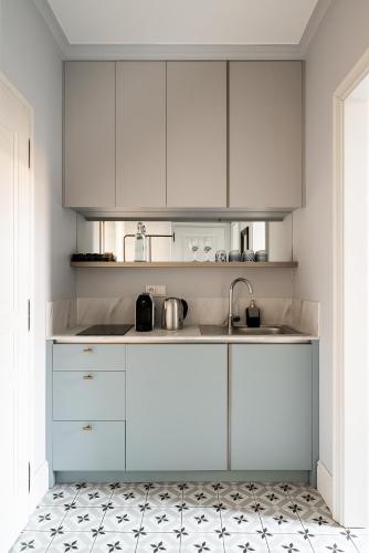 een keuken met witte kasten en een tegelvloer bij Moja apartments in Krakau