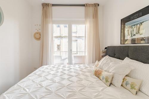 a bedroom with a large white bed with a window at TheKeyStudio, La casa dei Delfini in Bordighera