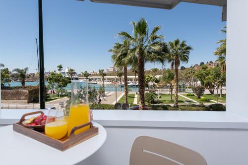 a tray of orange juice and fruit on a table with a window at iloftmalaga Puerto in Málaga