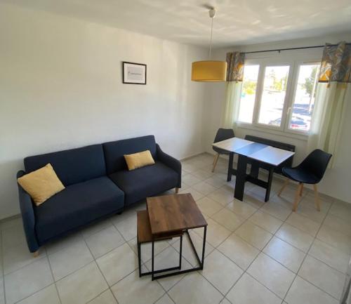 un salon avec un canapé bleu et une table dans l'établissement Le Myosotis Route des plages, à Narbonne