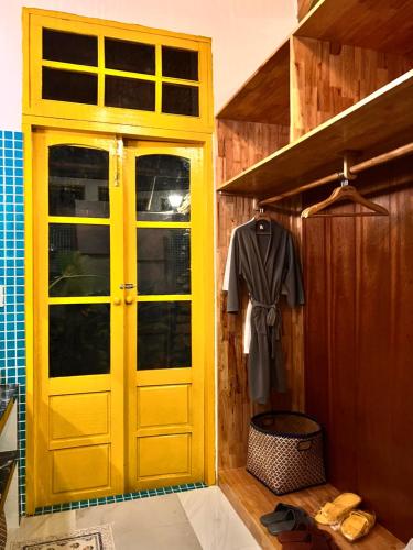 une porte jaune dans une pièce avec une chemise et des chaussures dans l'établissement Bently farm retreat Mũi Né- Deluxe Bungalow-01, à Ấp Phú Hiệp