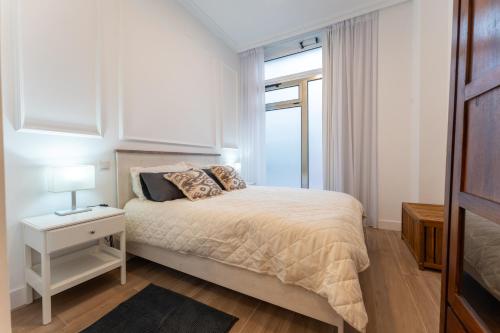 a white bedroom with a bed and a window at La bahia rooms in Santander