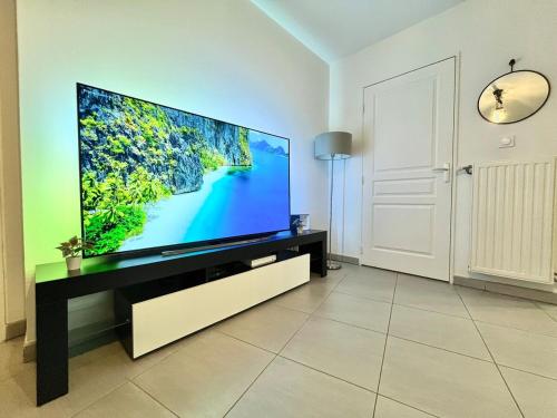 a living room with a large flat screen tv at T2 cosy avec parking - Goupama Stadium LDLC Arena in Décines-Charpieu