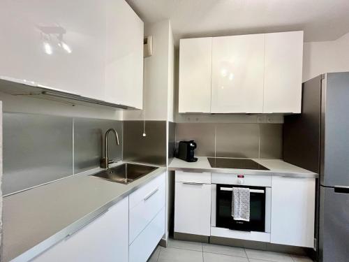 a kitchen with white cabinets and a sink at T2 cosy avec parking - Goupama Stadium LDLC Arena in Décines-Charpieu