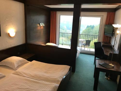 a hotel room with a bed and a large window at Logis Hôtel-Restaurant Aux Trois Roses in La Petite-Pierre