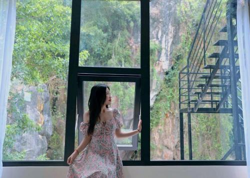 a woman in a dress standing in front of a window at Discovery Lodge Phong Nha in Cừ Lạc