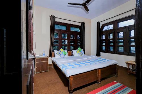ビムタルにあるHotel O Maha Maya Inn Home Stayのベッドと2つの窓がある寝室