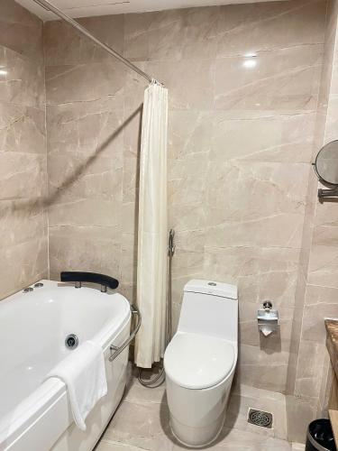 a bathroom with a white tub and a toilet and a bath tub at Muong Thanh Quy Nhon Hotel in Quy Nhon