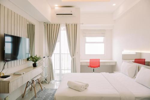 a white bedroom with a bed and a television at Simply Look Studio at Parkland Avenue Apartment By Travelio in Tangerang