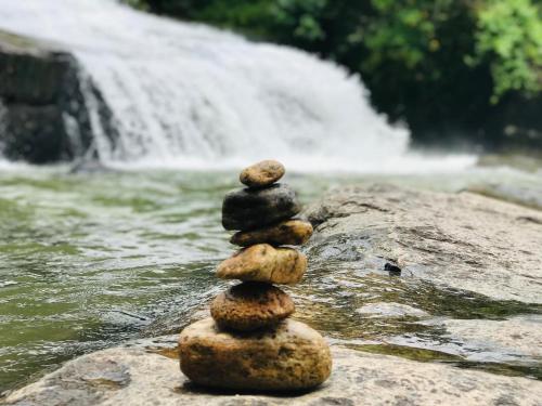 a stack of rocks sitting on a rock by a waterfall at Horizon View Mountain Bliss in Kandy