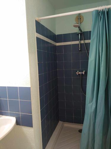 La salle de bains est pourvue d'une douche carrelée de bleu avec rideau de douche. dans l'établissement 2RB38A Appartement vue sur mer et proche plage, à Collioure