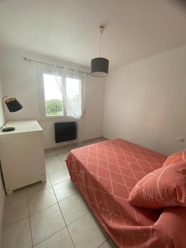 - une chambre avec un lit rouge et une fenêtre dans l'établissement Le Myosotis Route des plages, à Narbonne