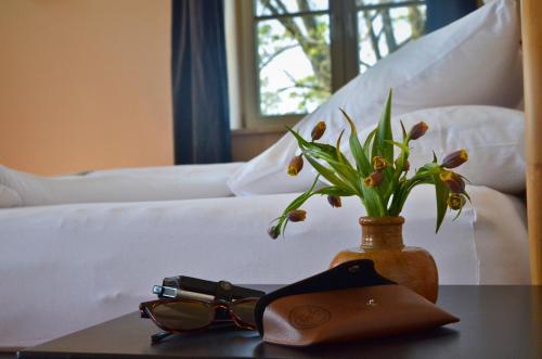 a table with glasses and a vase with flowers on a bed at An Den Wiesen Gasthaus am Finowkanal in Wandlitz