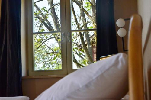 a bed looking out a window at a tree at An Den Wiesen Gasthaus am Finowkanal in Wandlitz