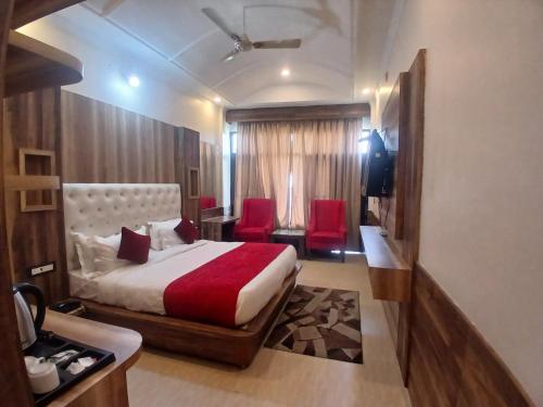 a hotel room with a bed and two red chairs at HOTEL GRAND HILL ,MALL ROAD ,Mcleodganj in Dharmsala