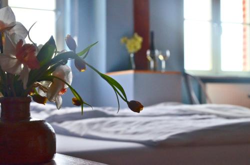 a vase of flowers on a table next to a bed at An Den Wiesen Gasthaus am Finowkanal in Wandlitz