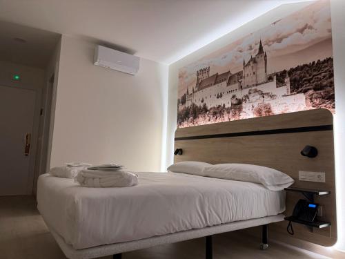 a bedroom with a bed with a painting on the wall at Hotel ELE Acueducto in Segovia