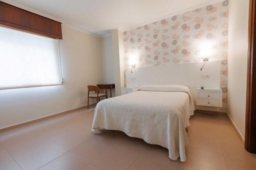 una camera da letto bianca con un letto e una finestra di Hotel O Cruceiro a Caldas de Reis