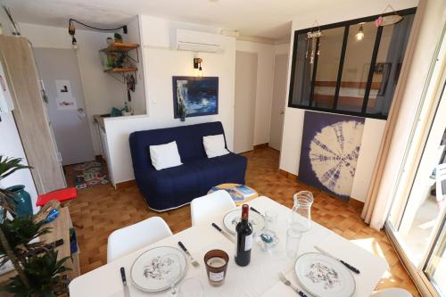 un salon avec une table et un canapé bleu dans l'établissement St cyprien appartement vue mer et piscine, à Saint-Cyprien