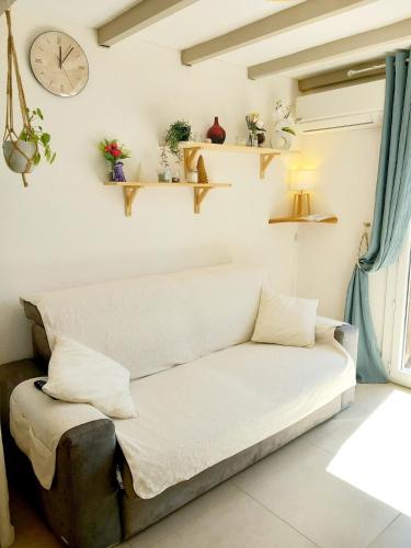 a couch in a living room with a clock on the wall at Maisonnette au calme in Saint-Vallier-de-Thiey