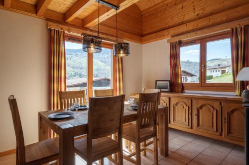 une salle à manger avec une table, des chaises et des fenêtres dans l'établissement Chalet Le Bas du Paradis, à La Bresse