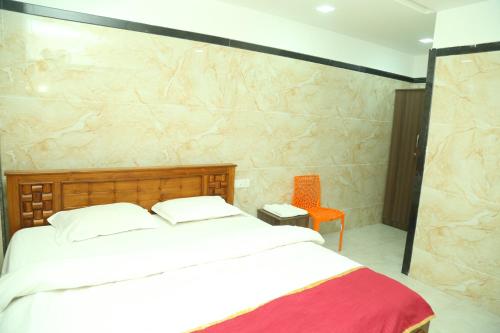 een slaapkamer met een bed en een oranje stoel bij S M Residency in Tiruppūr