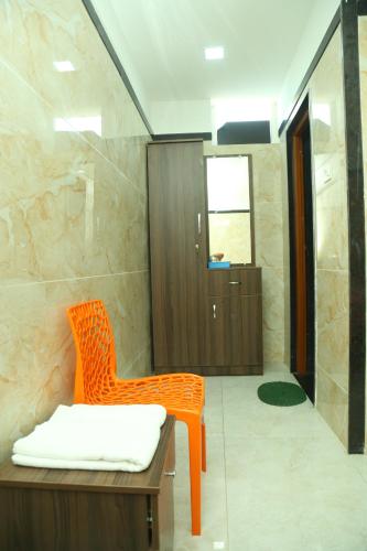 een oranje stoel in een badkamer met een douche bij S M Residency in Tiruppūr