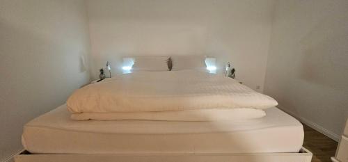a white bed with white sheets and pillows at Ferienwohnungen Das Finkhaus in Simonsberg