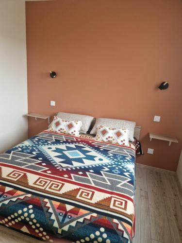 - une chambre avec un lit et une couverture colorée dans l'établissement Appartement des Aubépines, à Mées