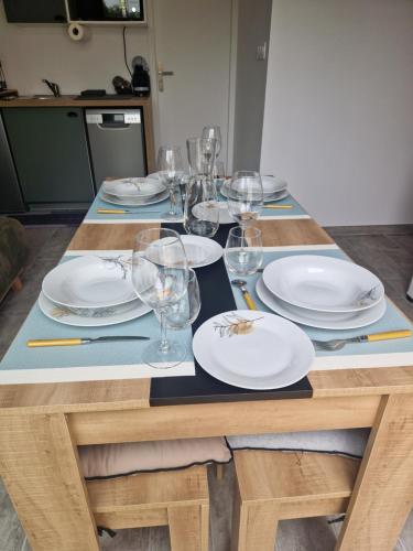 une table en bois avec des assiettes et des verres à vin dessus dans l'établissement Appartement des Aubépines, à Mées