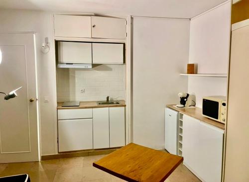 une petite cuisine avec des armoires blanches et un micro-ondes dans l'établissement Marlyn, à Cannes