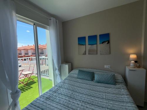 a bedroom with a bed and a large window at Adosado privado playa in San Antonio