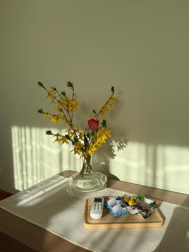 a vase with a rose and a remote control on a table at Comfy stay at Hill of Clouds in Rāmava