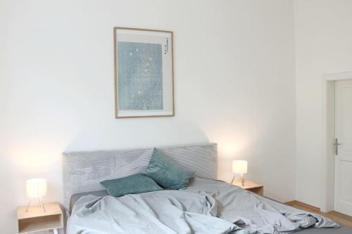a white bedroom with a bed with two lamps at Apartment Two am Stadtpark in Villach